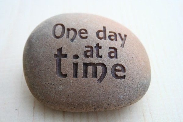 Stone with "One day at a time" carved in it.