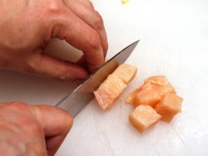 Someone cutting chicken meat