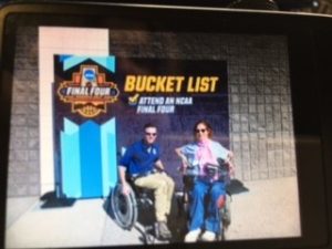 Happy on Wheels at the Final Four in 2017 in Phoenix under a sign that reads Bucket List.