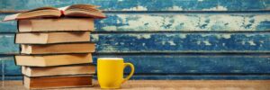 A stack of books next to a coffee mug.