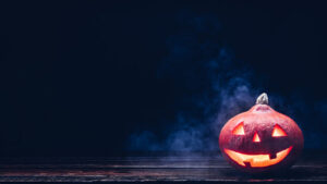 A jack-o-lantern in front of a misty dark sky.