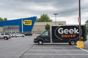 Photo of a Best Buy parking lot with a Geek Squad truck in it.