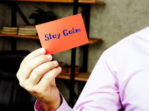 Photo of a person's arm and hand holding a note that says, "Stay calm."