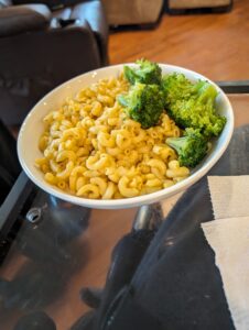 A dish of macaroni and cheese with some fresh broccoli.