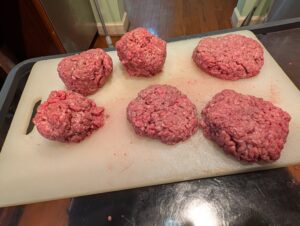 Photo of 6 hamburgers;  3 formed and 3 in the shape of a ball.