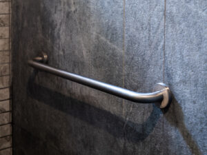 Photo of a grab bar attached to a tile wall.