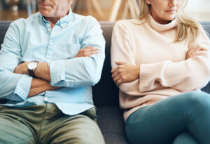 Two people sitting next to each other but not looking at each other, with their arms crossed.